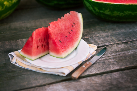 Sliced watermelon on plate with knife on wooden tableの写真素材