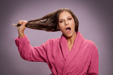 Shocked woman holding her dry damaged hair, haircare problems conceptの写真素材