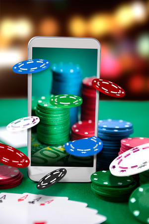 Online casino. Smartphone and poker table with card chips on screen. Online poker game. Poker application.の写真素材