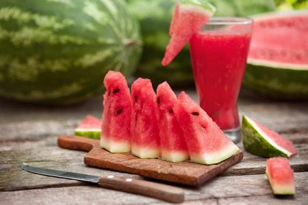 Chopping board with watermelon,watermelon juice and cutlery on the tableの写真素材
