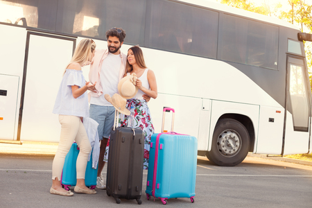 Young hipster friends travel on vacation by bus, they standing front of bus and waiting for go-offの写真素材