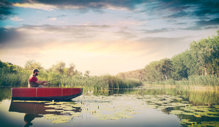 young man fishing in lake surrounded beautiful natureの写真素材