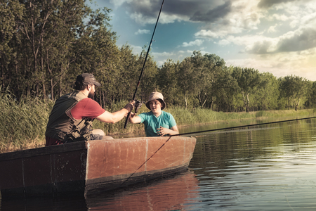 father and son fishing in wooden boatの写真素材