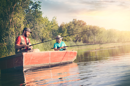 Father and son concentrate with fishing rods and look at the surface of the lake's waterの写真素材