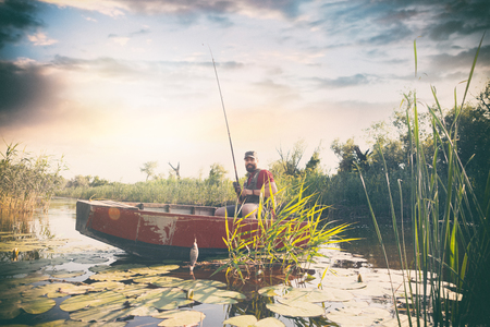 fisherman with fishing rod on which hangs caught fishの写真素材