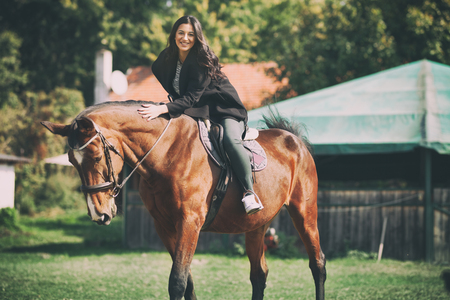 Beautiful smiling woman on horseback, having fun with horse on ranchの写真素材