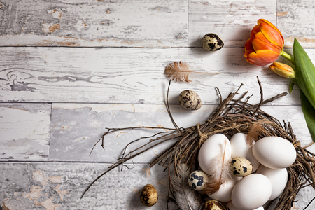 Quail and chicken eggs in a rustic nest on a wooden boardの写真素材