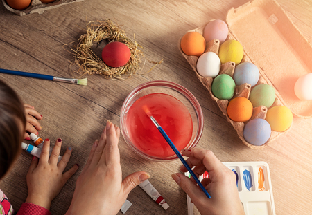 Mother assisting girl in painting Easter eggsの写真素材