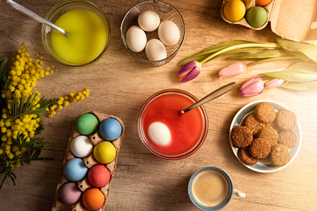 Table with colored eggs and paint for homemade coloring, Easter coming backgroundの写真素材