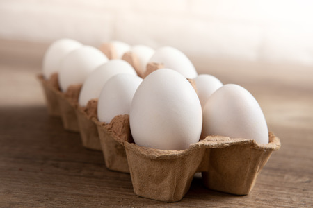 Close up of raw chicken eggs in egg box on brown wooden background, organic food from nature good for healthの写真素材