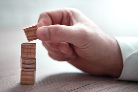 Hand of man has piling up and stacking a wooden block. Plan and strategy in business, risk conceptの写真素材