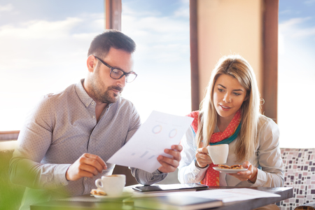Two business people sitting in cafe. They are drinking coffee and finishing their work out of office.の写真素材