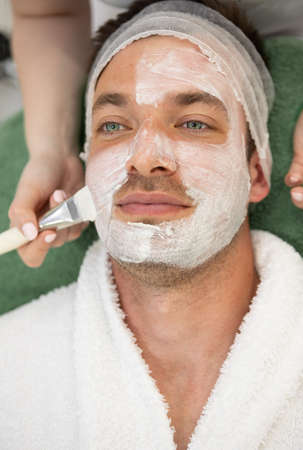 young man receiving skincare cosmetic treatment at spa salonの写真素材