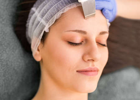 Close-up of beautiful woman receiving ultrasound cavitation facial peeling. Beauty treatment. Beauty, spa, cosmetology and skincare concept. Cosmetologically clinicの写真素材