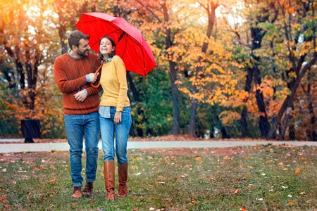 Young couple man and woman walk under an umbrella in wet rainy weather, walk October loversの写真素材