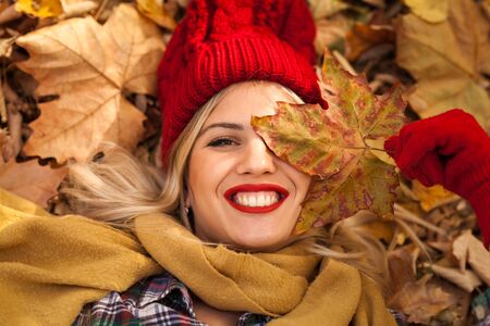 Happy fun in autumn.  Nice smiling woman playing with autumn leaves