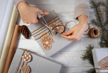 Womanâ€™s hands decorate gift for Christmas with cardboard gingerbread. Christmas gift...