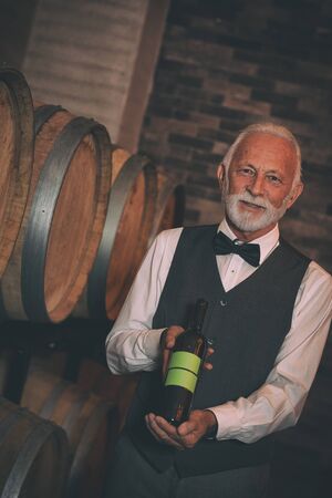 Sommelier with bottle of wine in winery cellarの写真素材