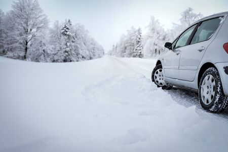 Car with winter tyres installed on wheels in snowy outdoors road