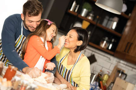 Young happy family preparing bakery together and have funの写真素材