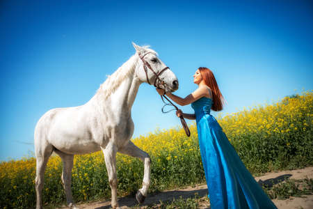 Portrait of beauty red haired woman with horse in the fieldの写真素材