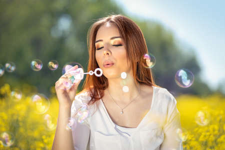 Young woman with soap bubbles on rapeseed field