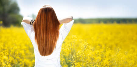 Beautiful long hair. Beauty with luxurious straight red hair in yellow flowers.  Lady with long smooth shiny straight hair. Hairstyle, cureの写真素材