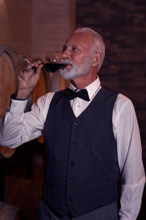 Senior man with beard drinking and tasting red wine