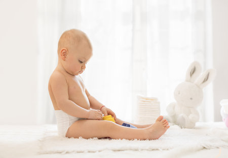 Baby in diaper sitting and playing on table for changingの写真素材