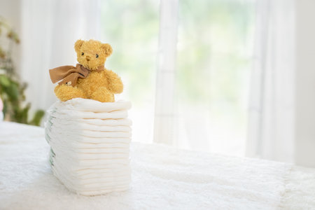 Baby diapers stack cute teddy bear sitting on top. Newborn nappies conceptの写真素材