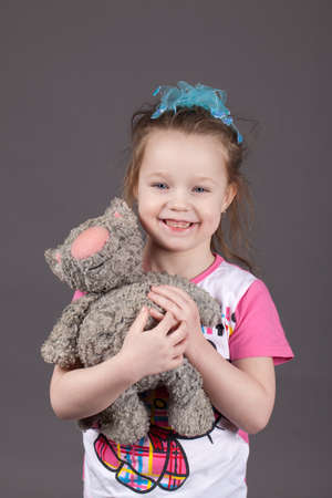 Little girl playing with a toy cat in studio. Gray backgroundの写真素材