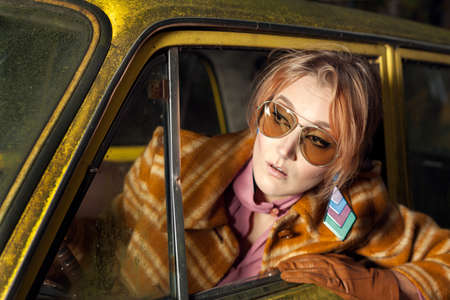 1970s vintage lady sitting in a retro carの写真素材