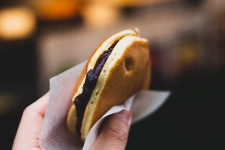 Hand holding a Japanese red bean pancake, dorayaki.の写真素材