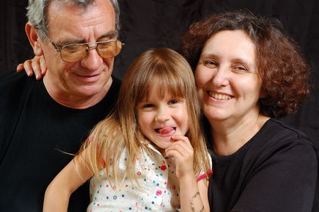laughing happy grandparents with 5 year old granddaughter showing tongue