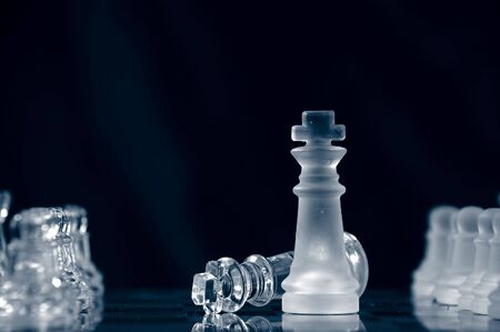checkmate with glass king lying on chessboard against black backgroundの写真素材