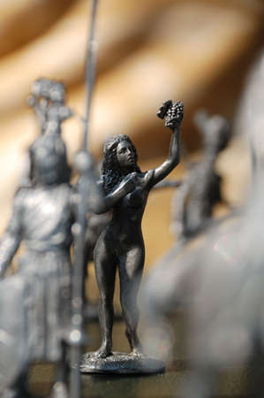 tin statuette of a nude woman with grapes surrounded with other figuresの写真素材