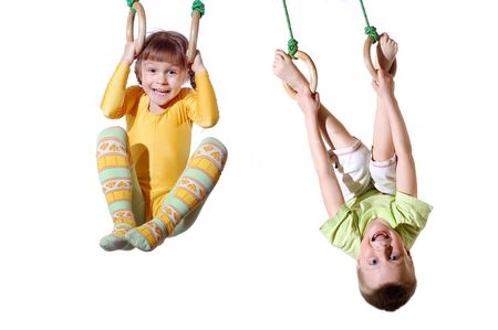 two 4 year old kid hanging on gymnastic ringsの写真素材