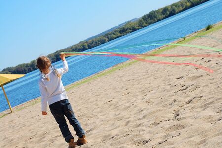 child playing with ribbons on the autumn beachの写真素材