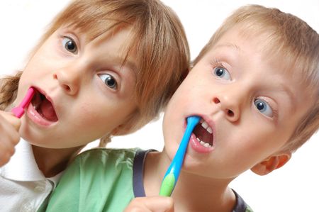 two cute kids brushing their teeth over white backgroundの写真素材