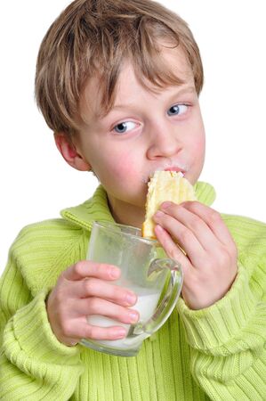 portrait of an elementary age boy eating cake and drinking milkの写真素材