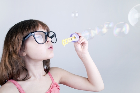 child with glasses blowing soap bubblesの写真素材