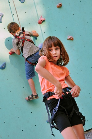 elementary children with climbing equipment against the training wallの写真素材