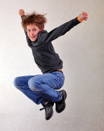 Portrait of a cute  sportive, cheerful happy boy with his hands up jumping and dancing. Childhood,...