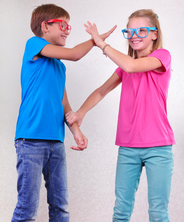 portrait of playful brother and sisiter with sunglasses  fighting and having funの写真素材