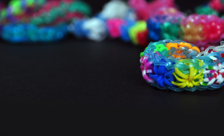 Colorful background rainbow colors rubber bands loom bracelets on black background. Copy space.の写真素材