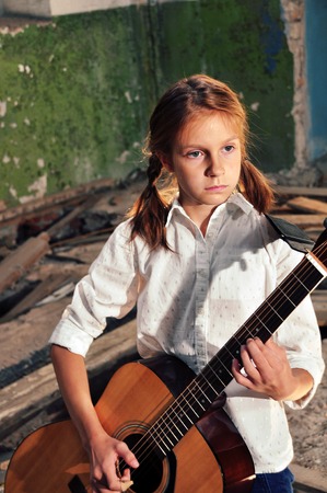 Beautiful young teenage girl with guitar musical instrument guitar in old ruined room Grunge...