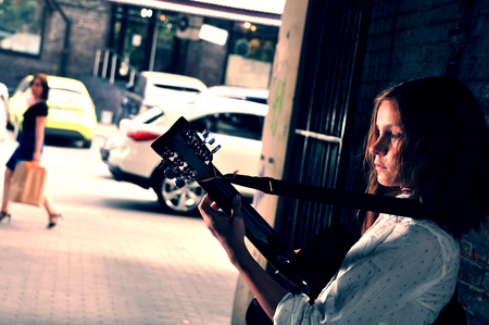 Pretty young teen girl playing acoustic guitar in the street. Toned.の写真素材