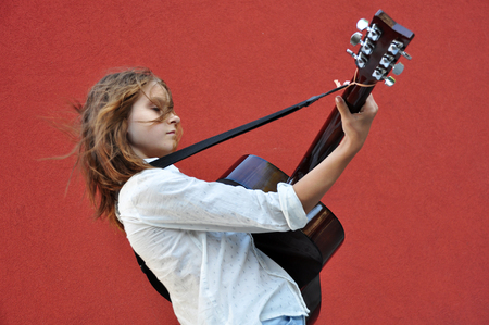 Pretty young teen girl playing acoustic guitar in the street.の写真素材