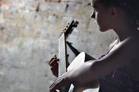 Beautiful young teenage girl playing acoustic guitar in the streetの写真素材