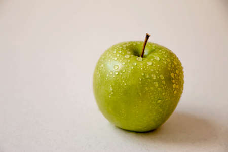 Green apple on a white background with water droplets